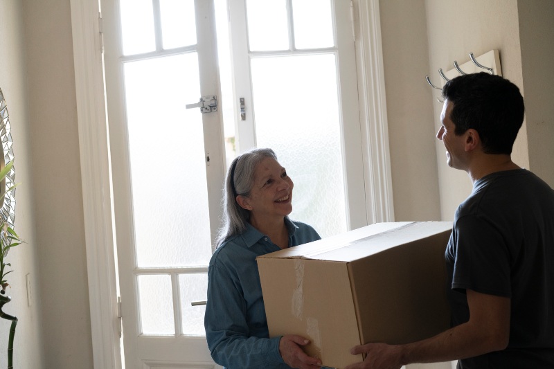 Young man helping elderly woman move in Houston