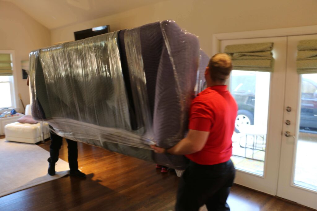 two men moving a couch in a living room